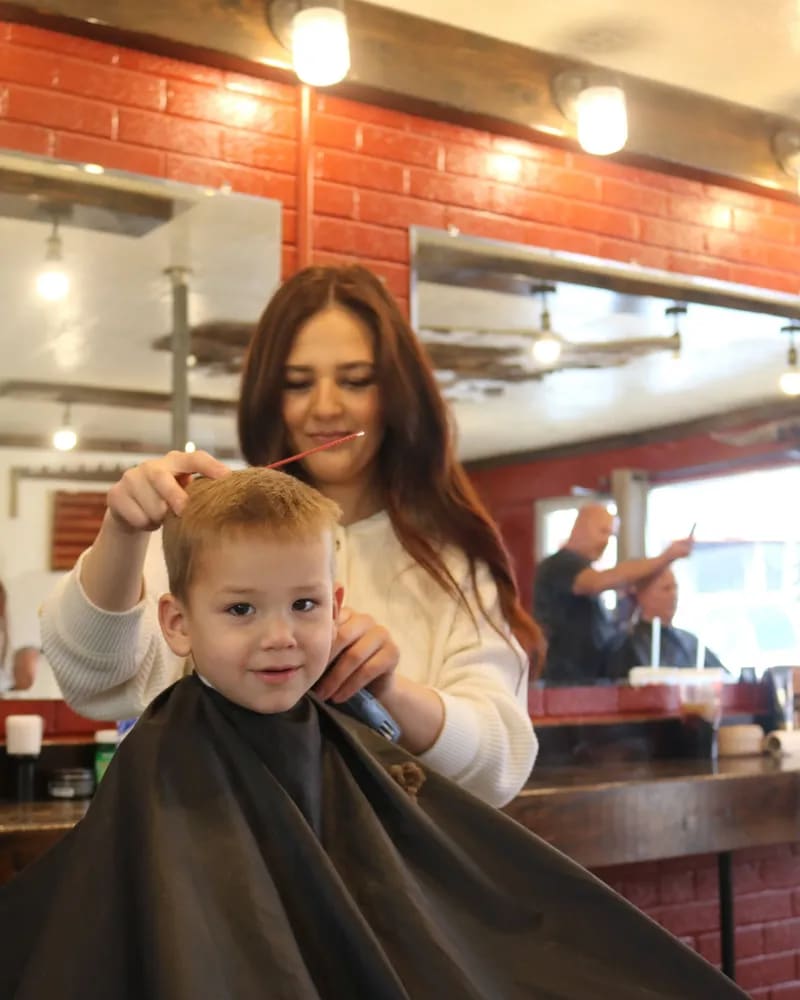 Smiling young boy in a black cape getting a haircut